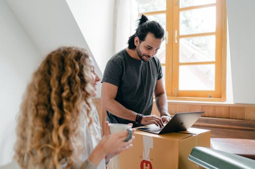 Happy couple using laptop on carton box