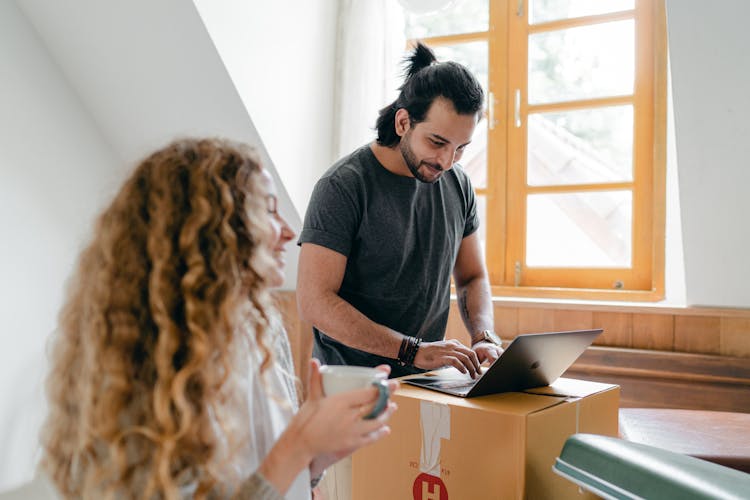 Happy Couple Using Laptop On Carton Box