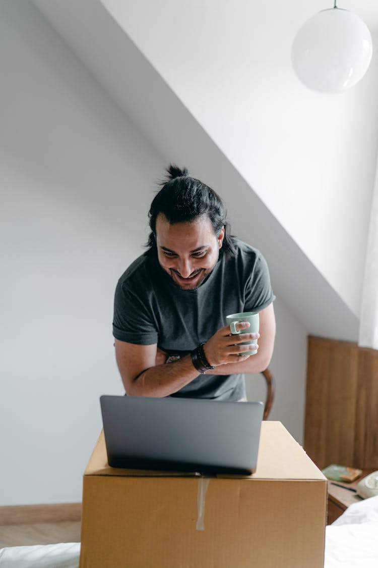 Happy Man Using Laptop Near Carton Box