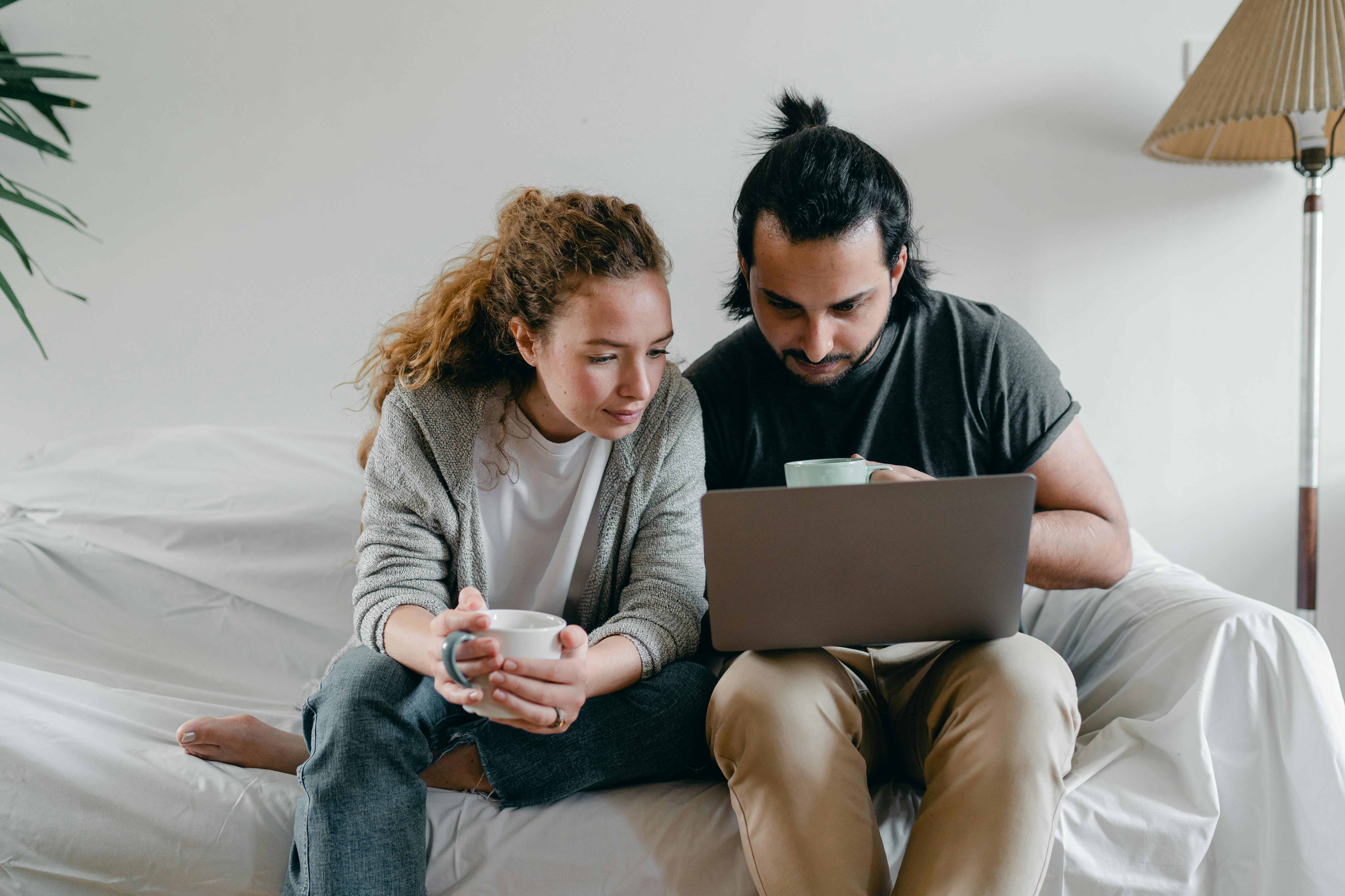 concentrated couple browsing laptop on sofa