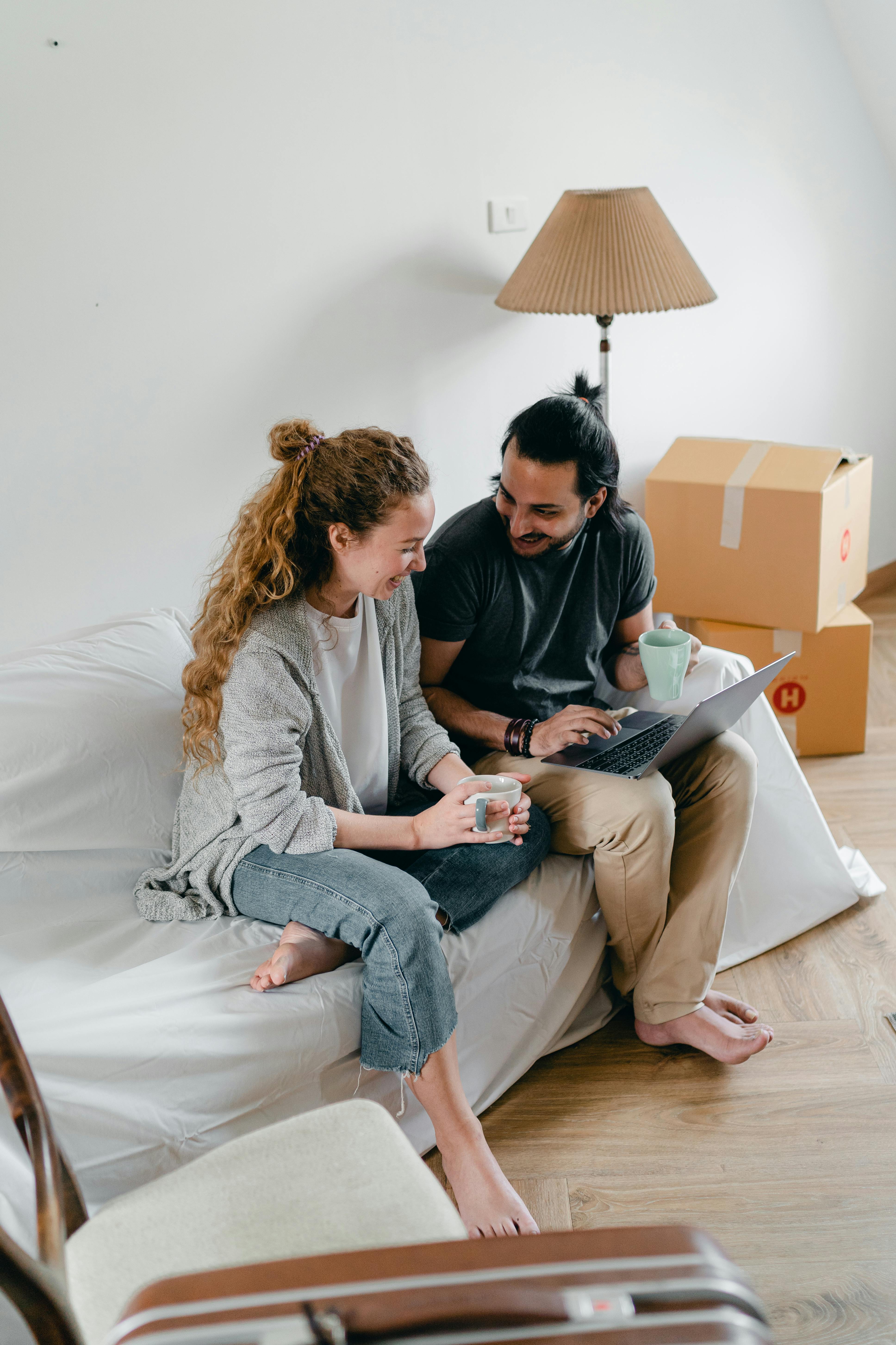 couple using laptop in room with packed boxes