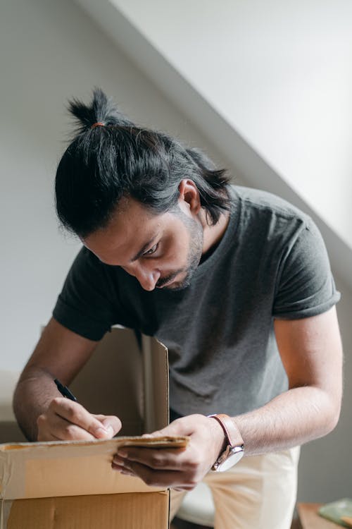 Free Serious man taking notes on carton box Stock Photo