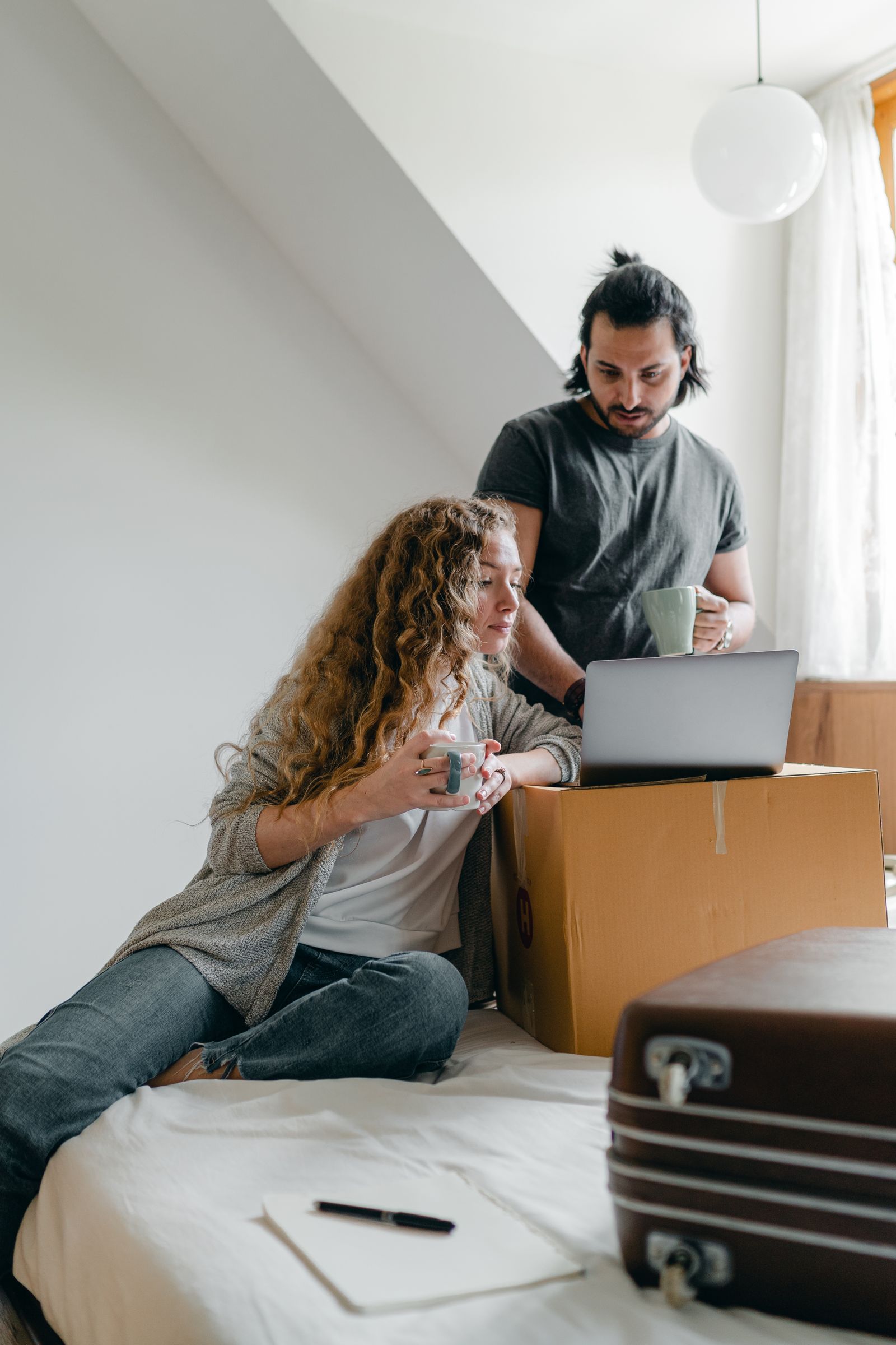 African guest using a laptop beside luggage in a comfortable BnB bedroom