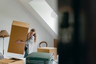一名妇女正在一间舒适、阳光明媚、家具很少的房间里打包箱子，准备搬迁