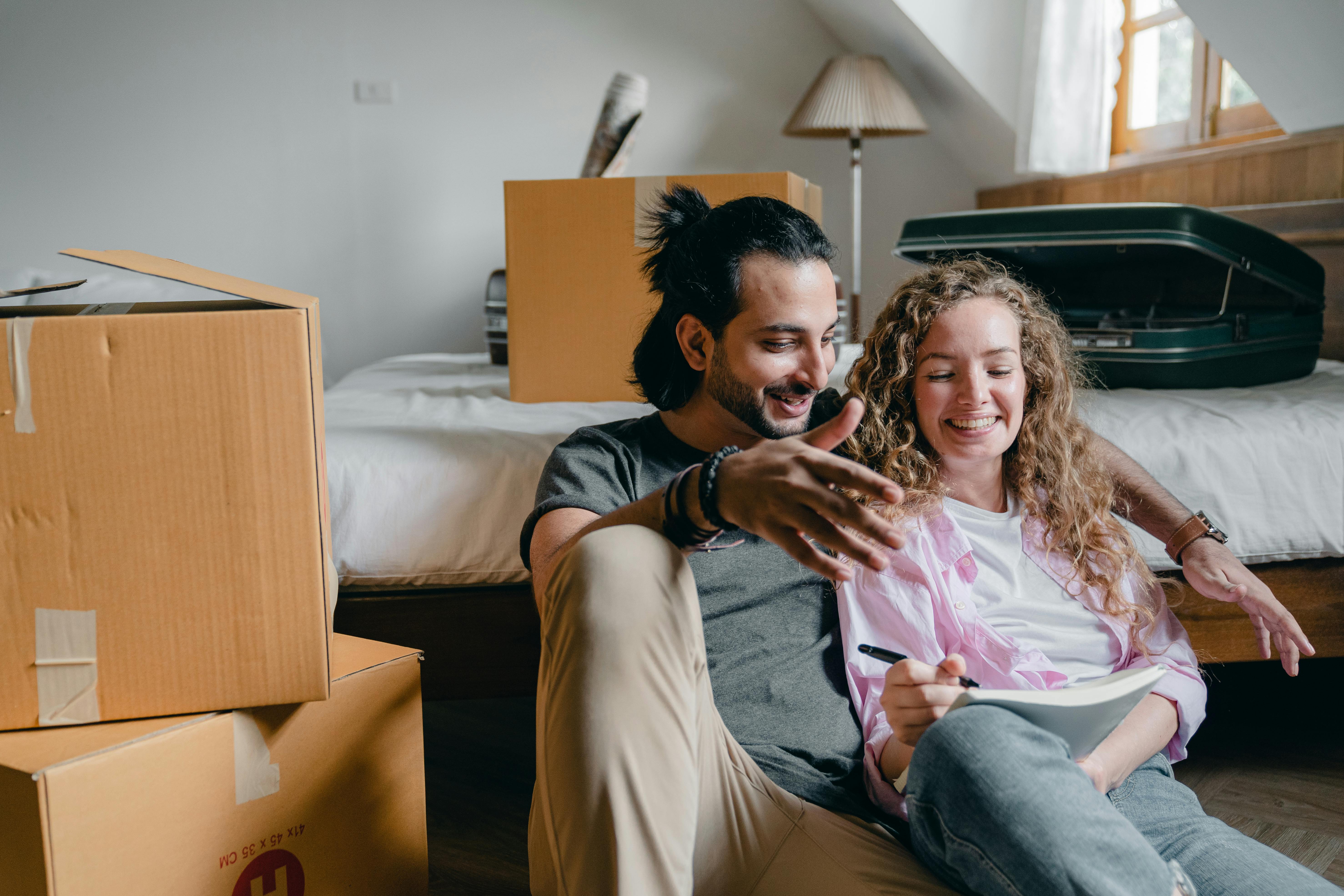 cheerful couple taking notes while moving to new house