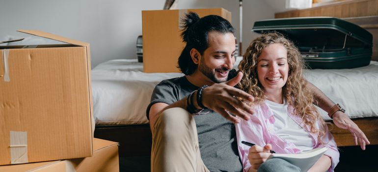 Couple reviewing a moving into your first place checklist beside moving boxes.