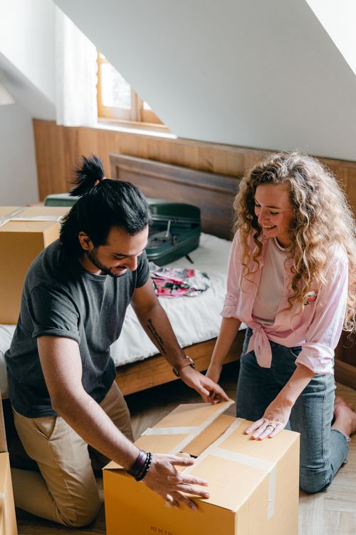 Cheerful people packing carton box in bedroom · Free Stock Photo