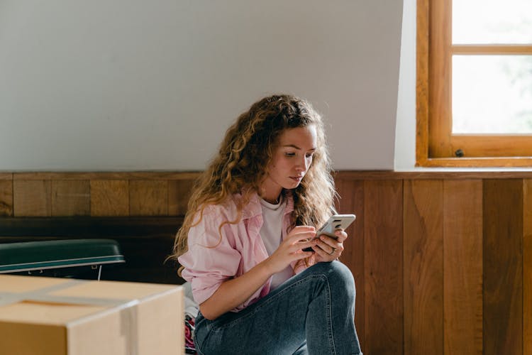 Young Woman Using Smartphone In New House