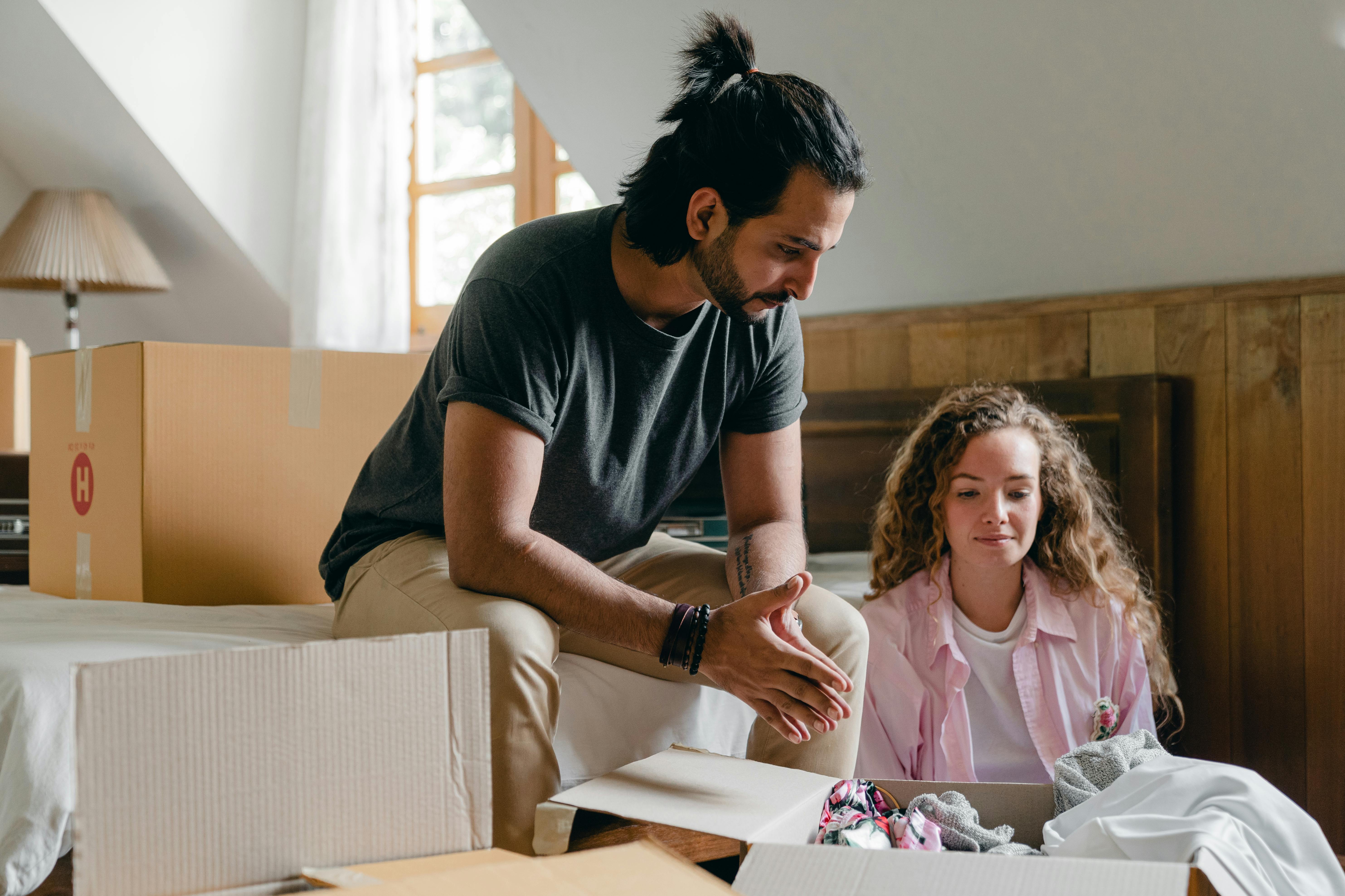 diverse couple unpacking carton boxes during relocation at new home