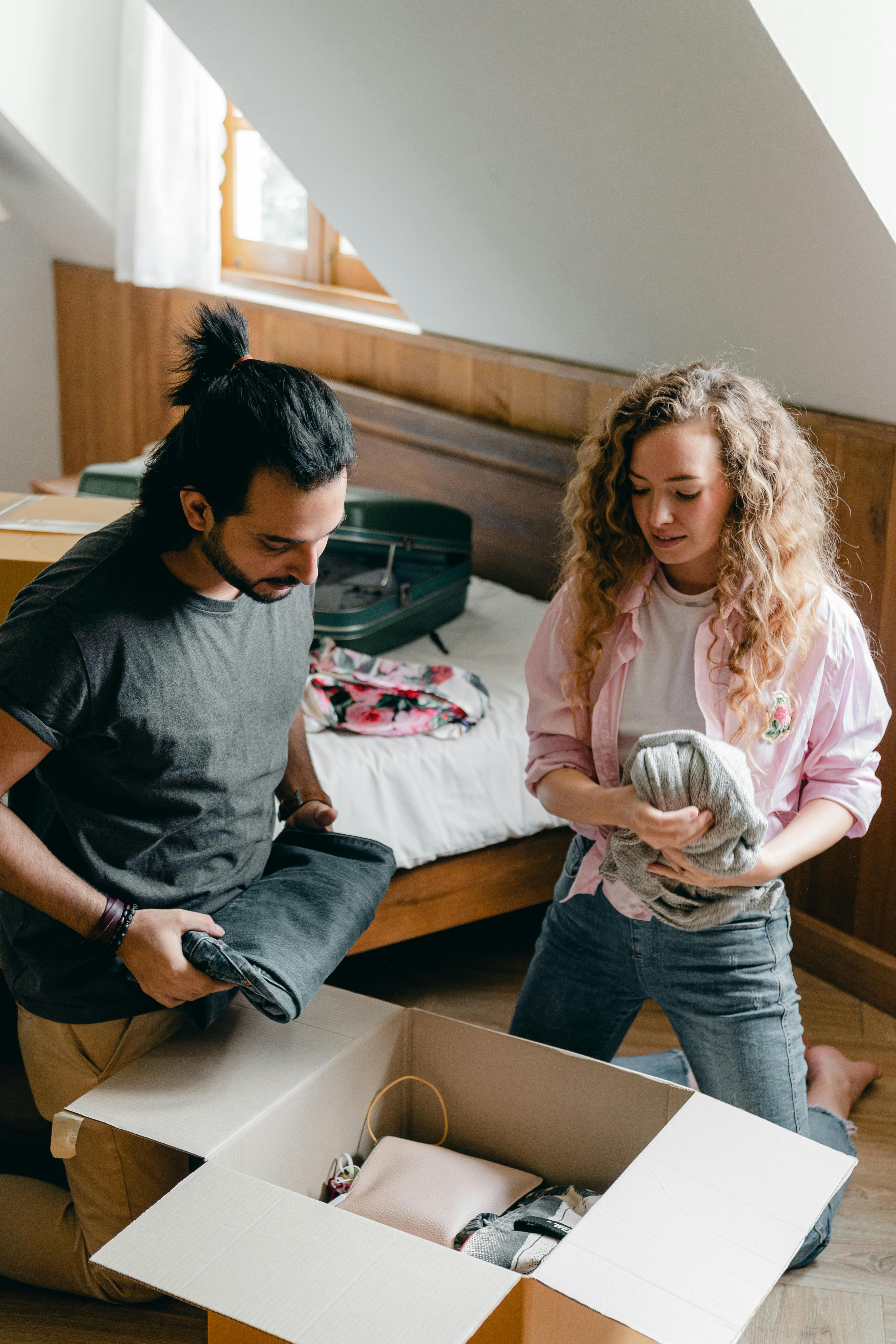 diverse man and woman unpacking stuff while relocating to new apartment