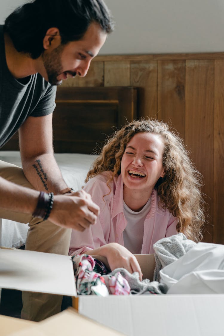 Cheerful Diverse Couple Unboxing Stuff In Bedroom Of New House