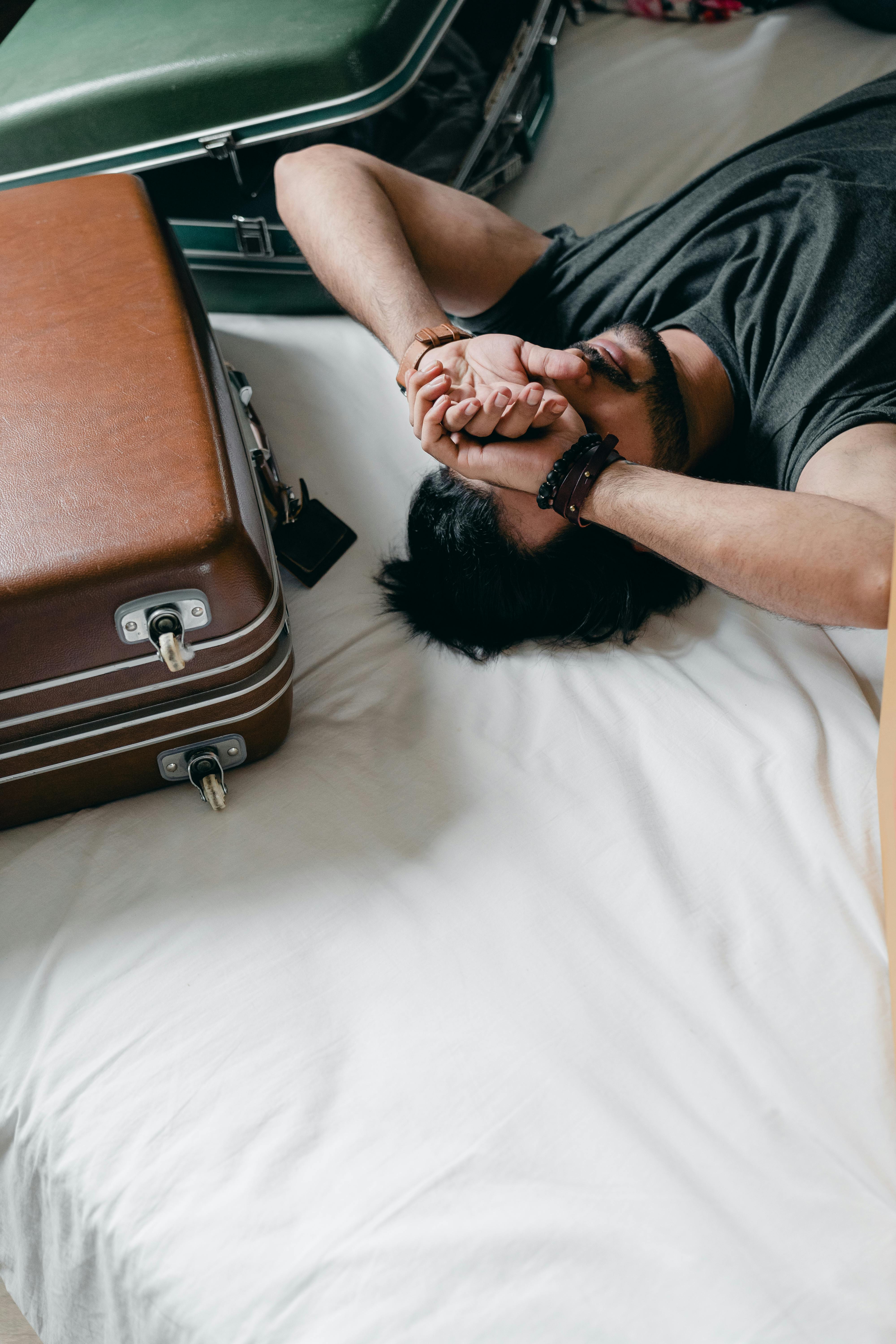 Tired ethnic man lying on bed during relocation in new house