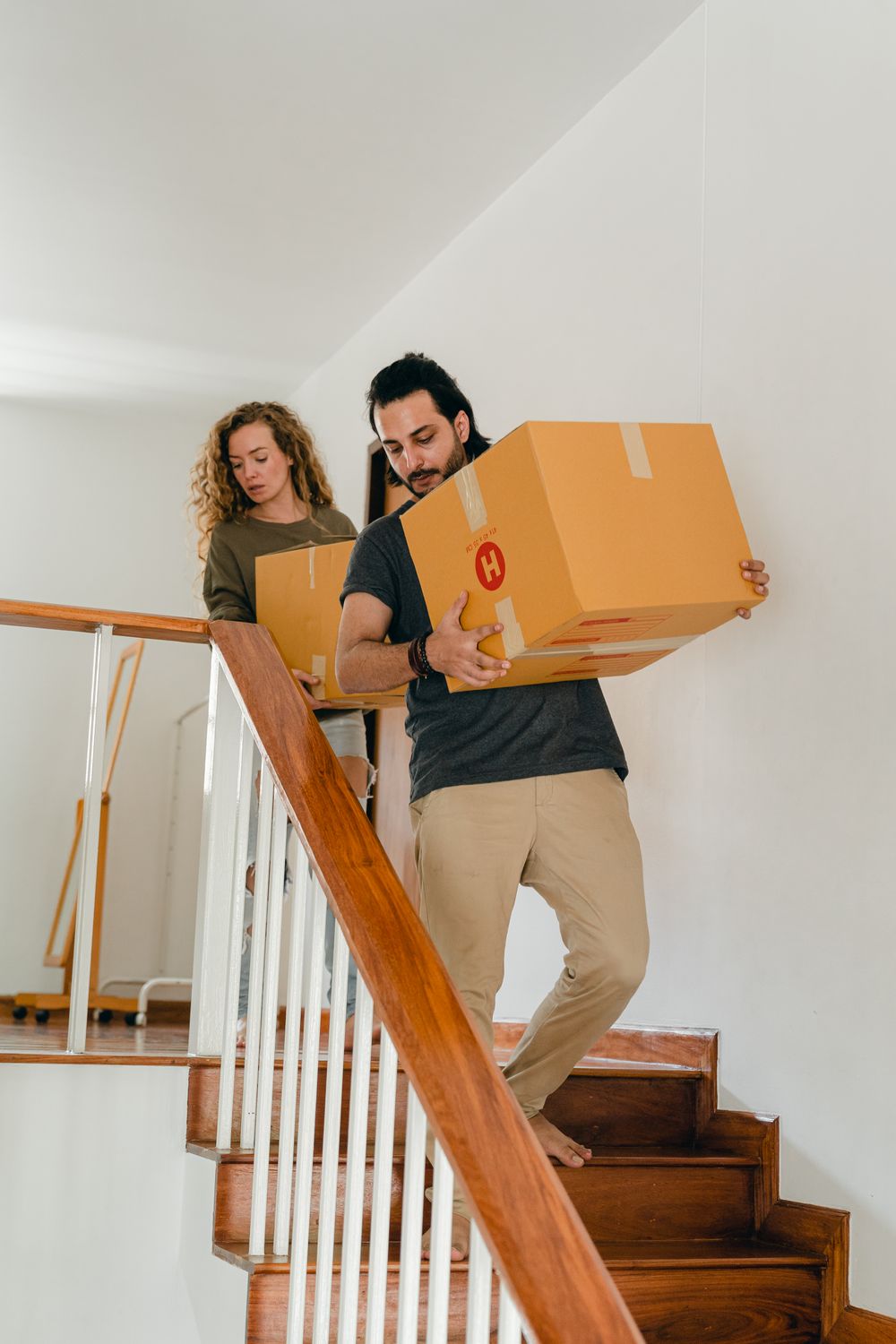 Couple carrying moving boxes downstairs during a house removal in London