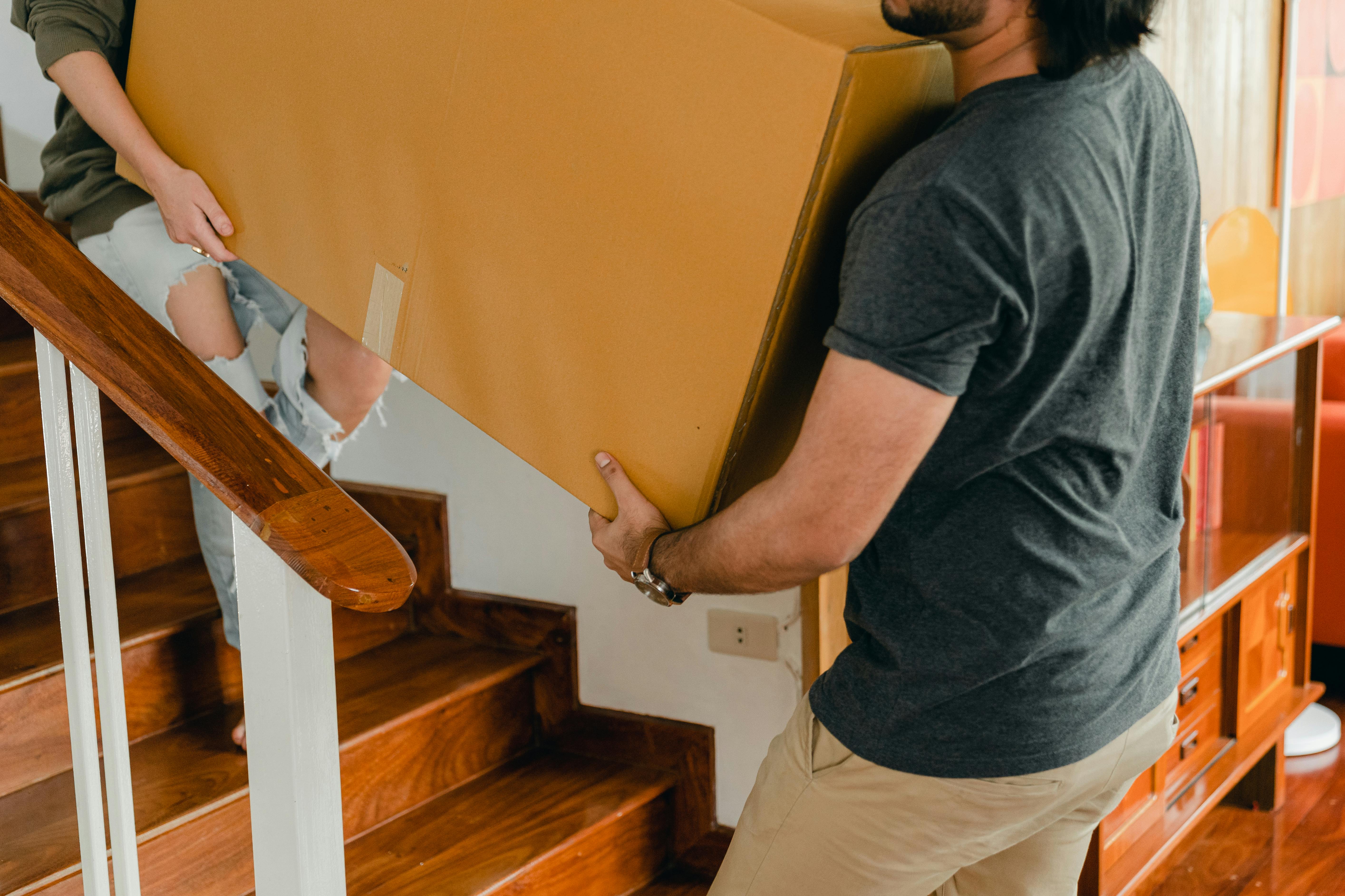 couple carrying personal items box down stairs