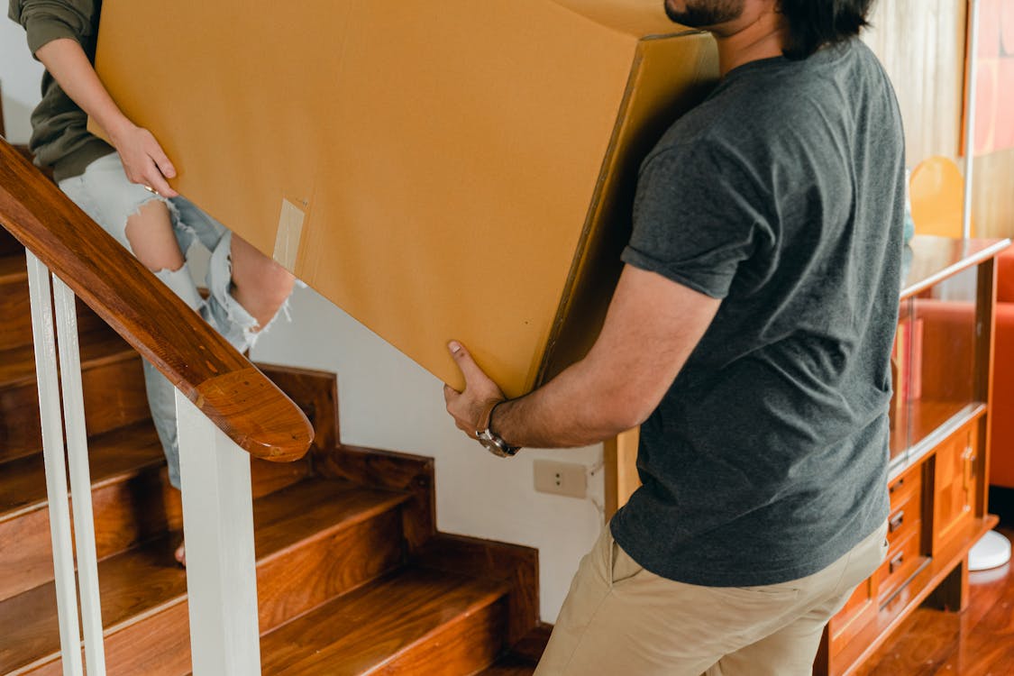 Couple carrying personal items box down stairs