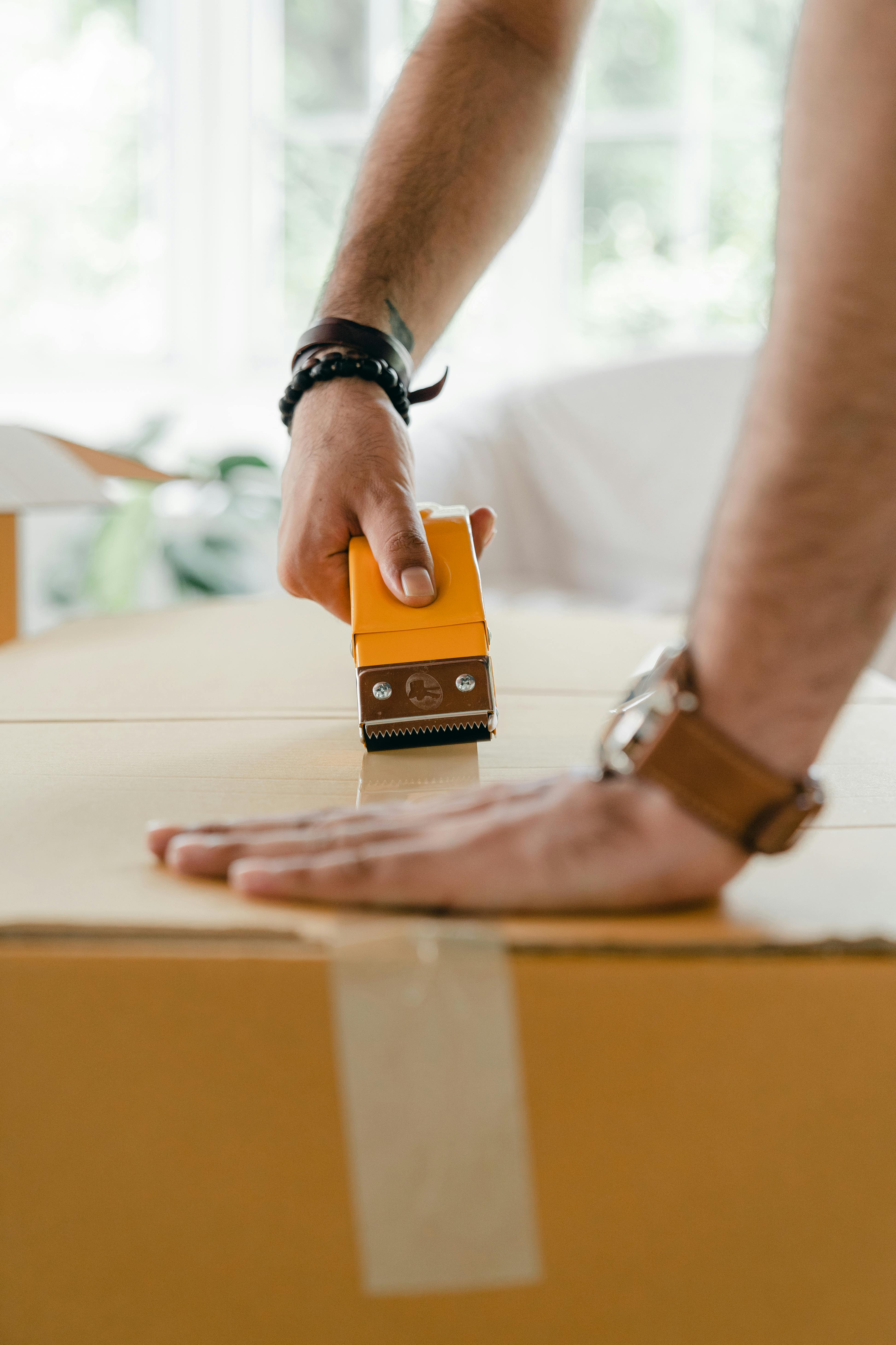 crop man using scotch tape dispenser for packing carton box