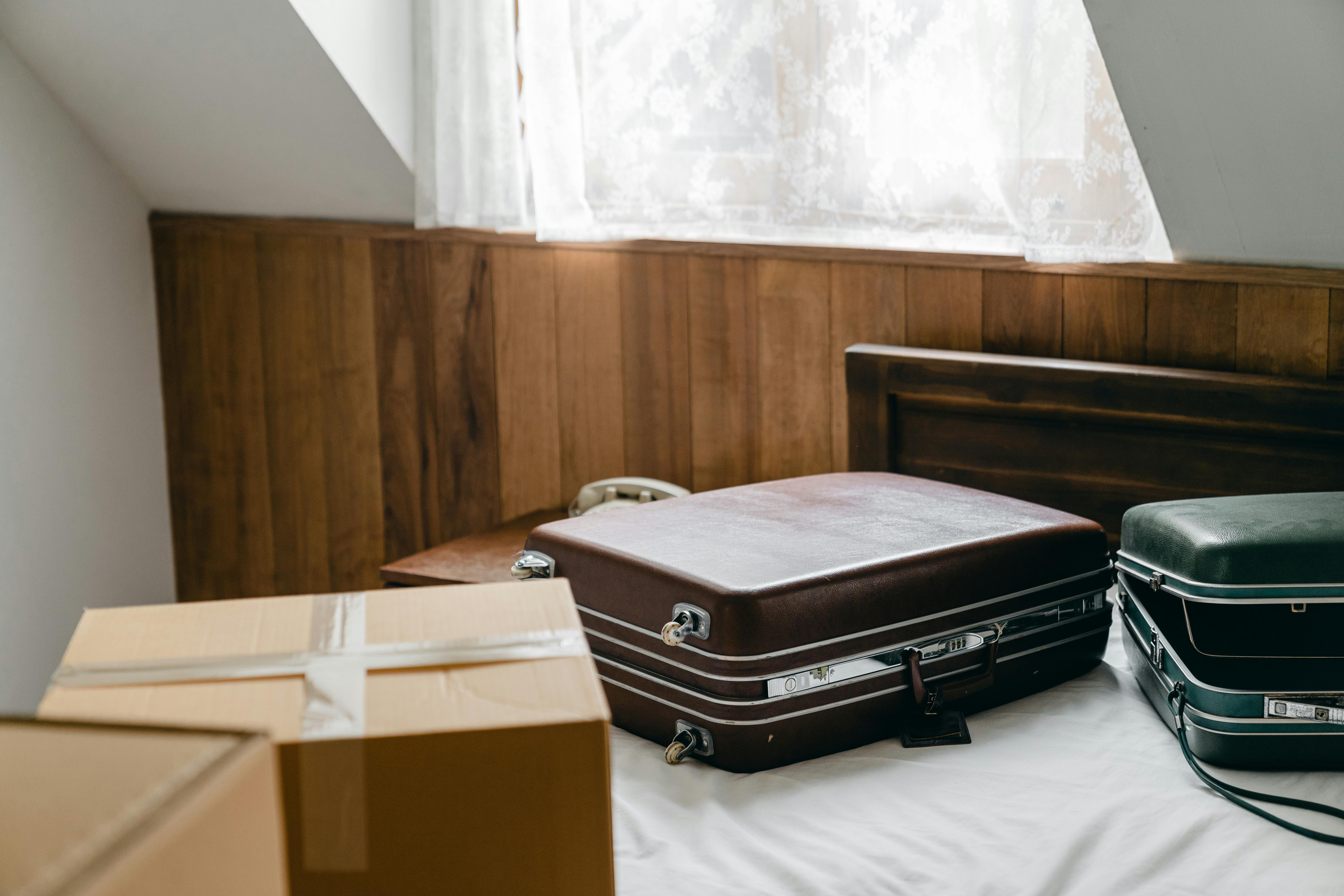 suitcases and packed boxes placed on bed in light room