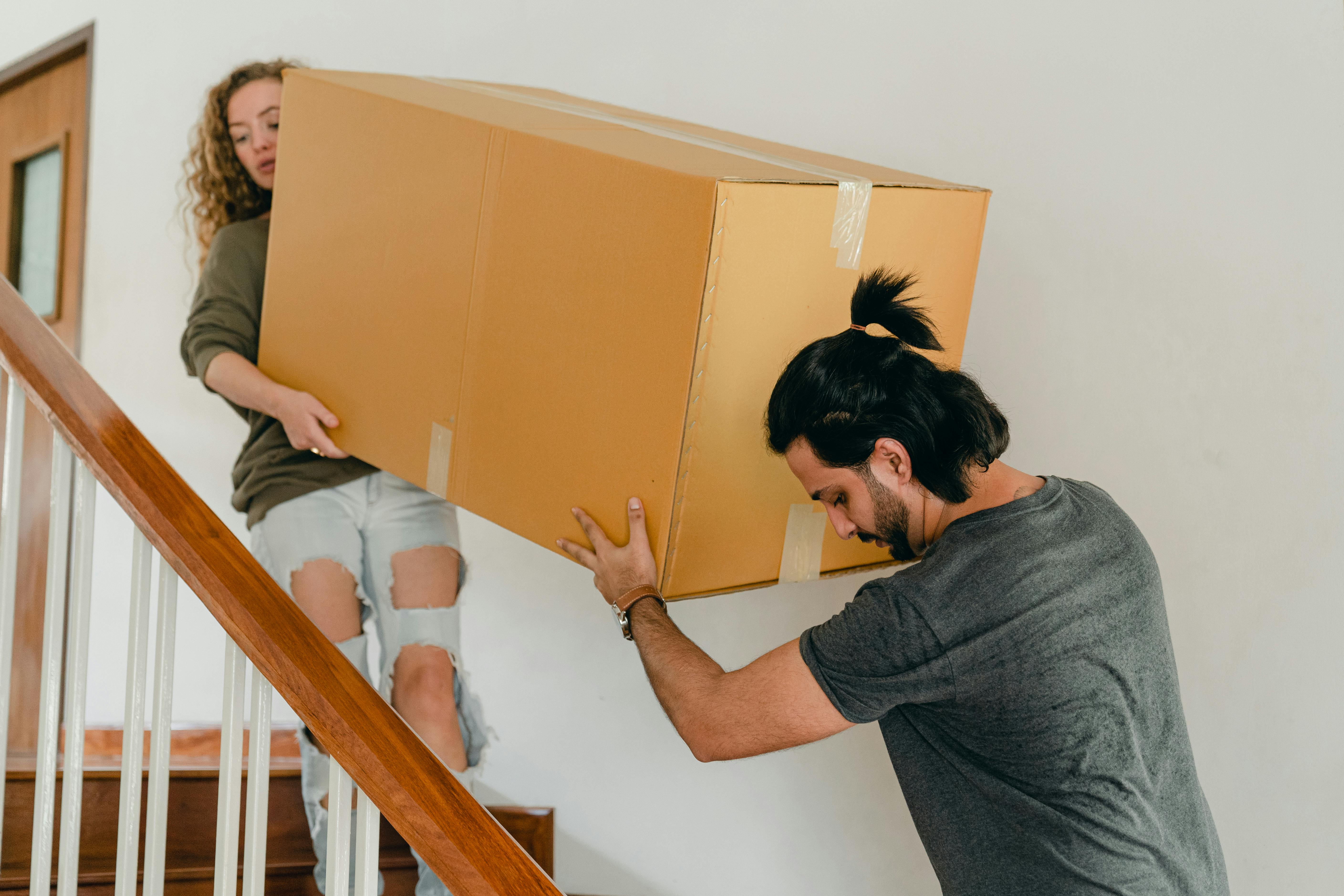couple carrying box down stairs in new apartment