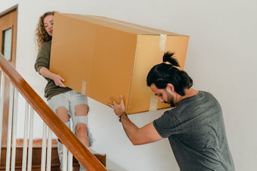 Couple carrying box down stairs in new apartment