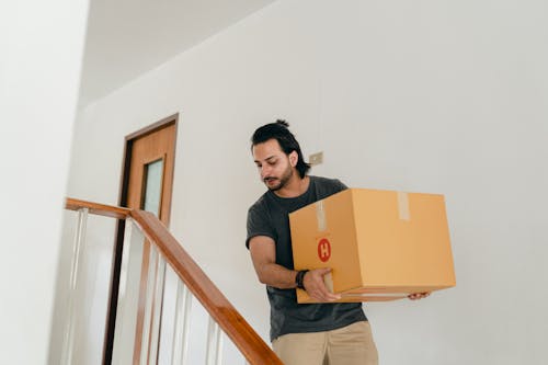 Adult man carrying box down stairs