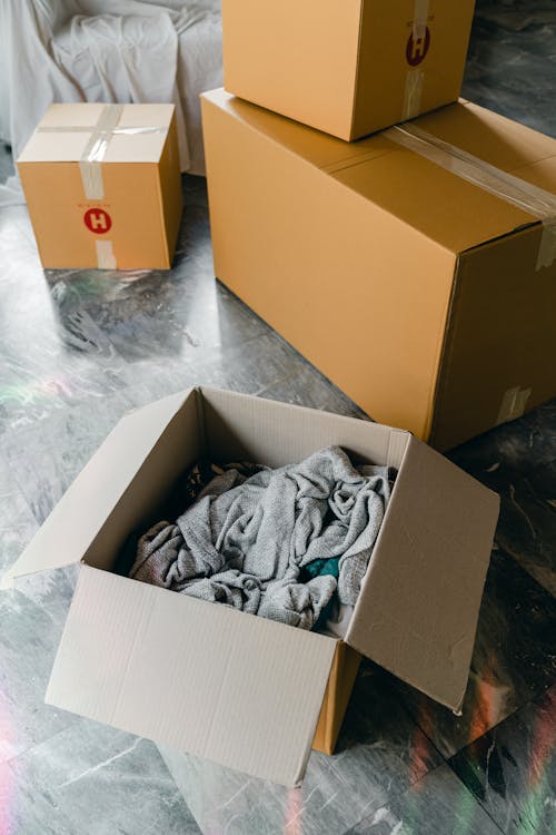 From above of cardboard boxes with packed items placed on floor in new apartment