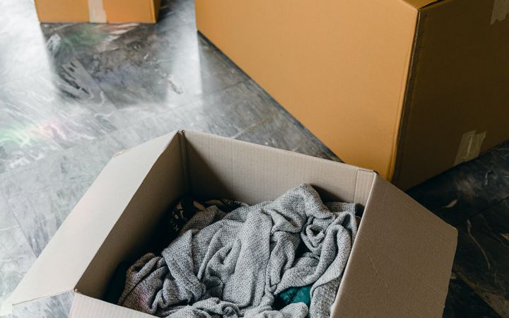 From above of cardboard boxes with packed items placed on floor in new apartment