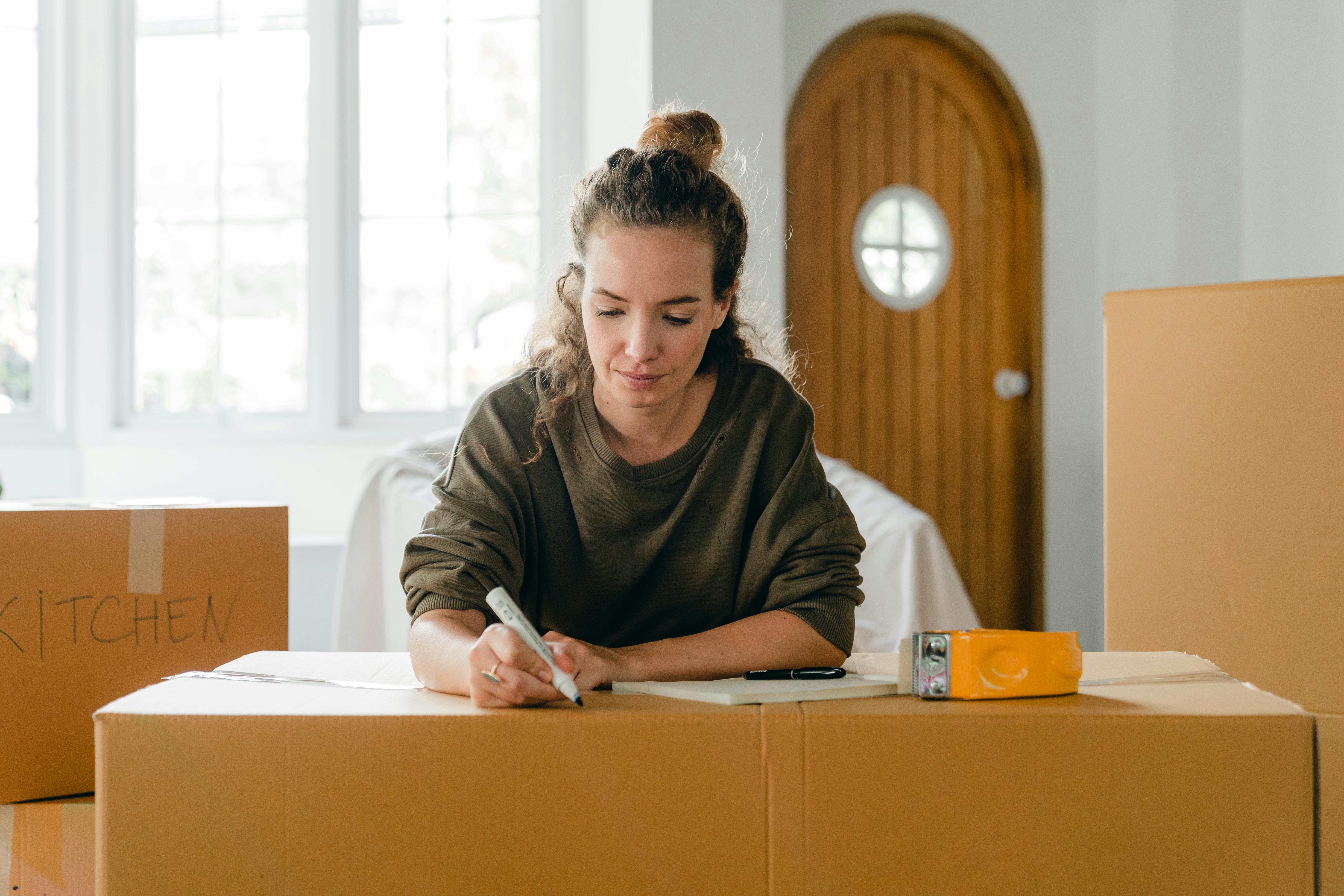 concentrated young lady preparing carton boxes for relocation