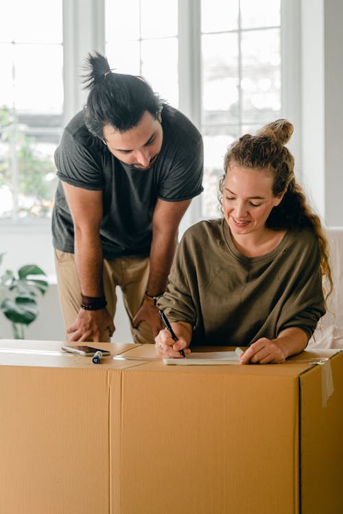 Free Young cheerful couple preparing for relocation after packing boxes Stock Photo