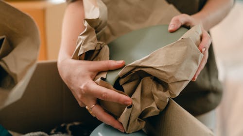 Crop woman with packing paper and belongings