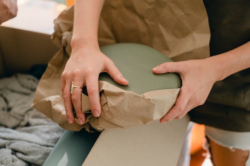 Free Crop young woman packing fragile goods for transportation Stock Photo