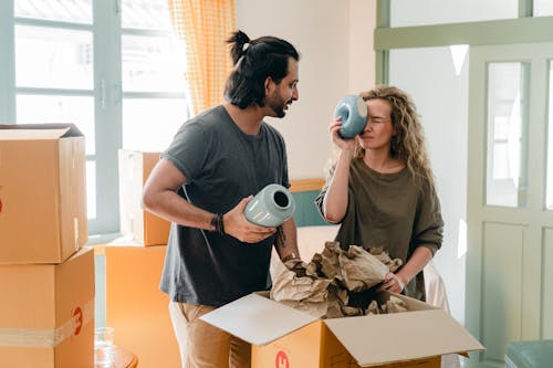 Free Multiethnic couple with ceramic vases and pile of cardboard boxes Stock Photo