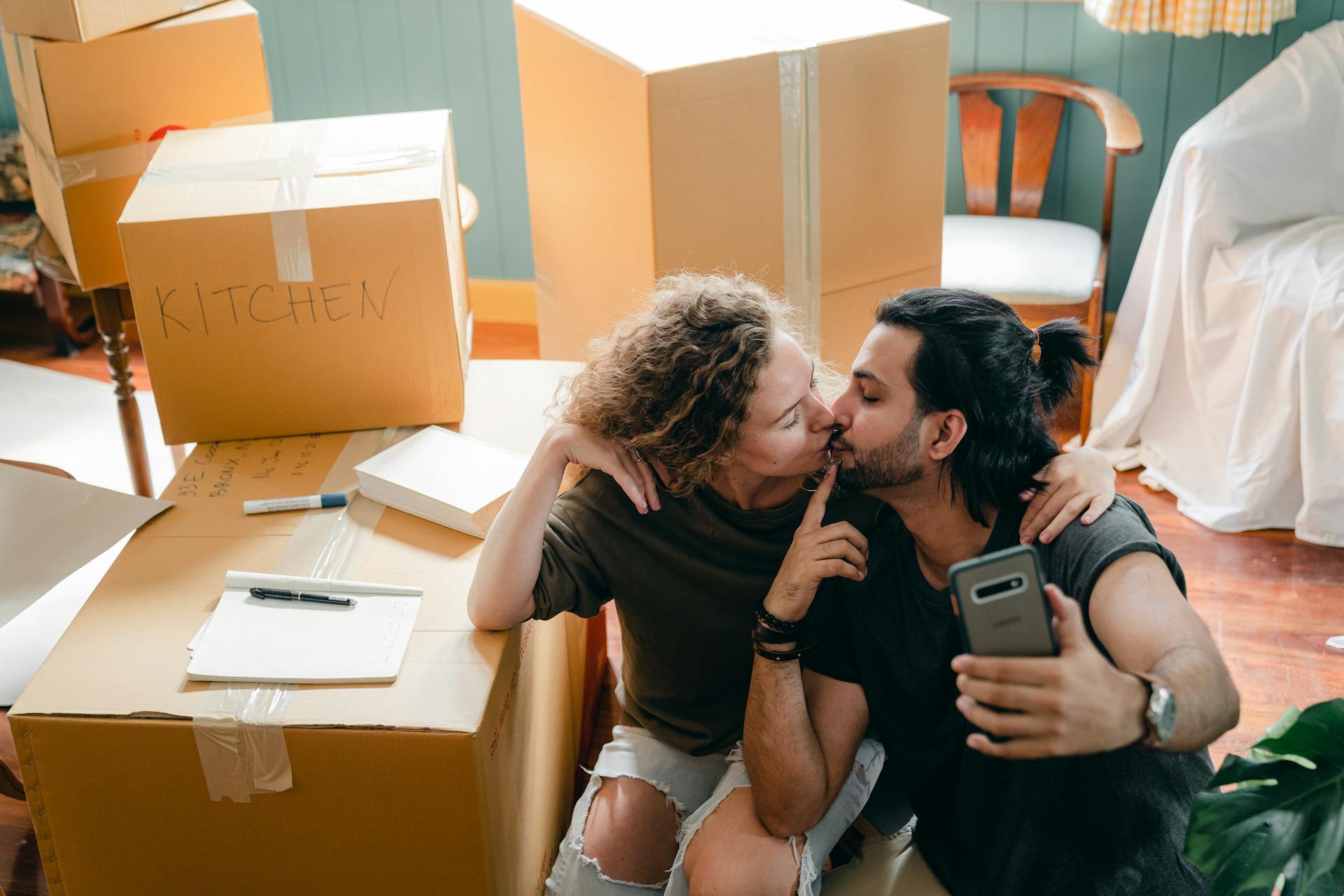 Affectionate couple taking a selfie while surrounded by moving boxes at home.