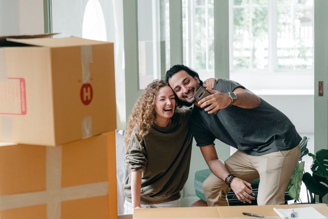 Cheerful couple taking selfie near carton boxes