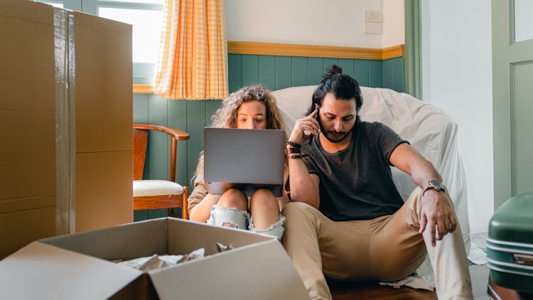 Concentrated Couple Using Laptop And Talking On Smartphone