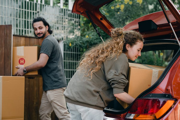 Diverse Couple Taking Things Out Of Car During Moving House