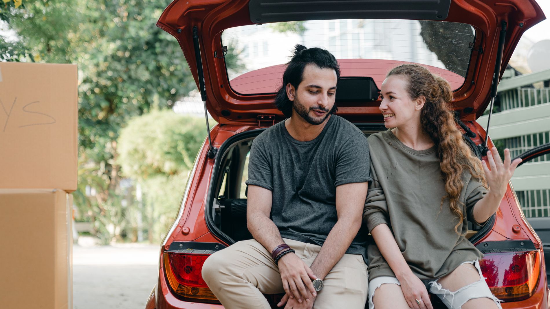 A couple talking happily while unloading their car on moving day