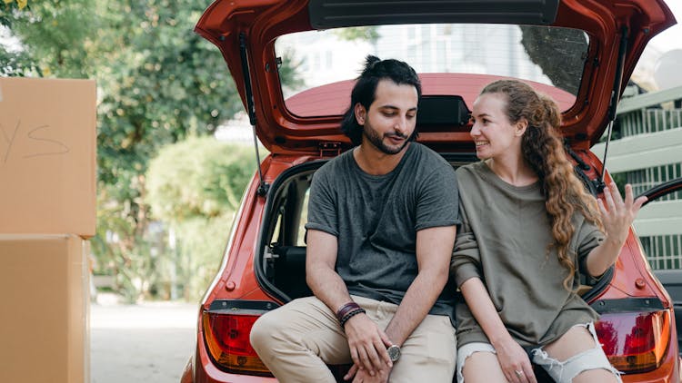 Young Diverse Couple Relaxing After Unpacking Car While Moving Home