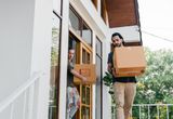 Couple carrying cardboard boxes while moving out of their home