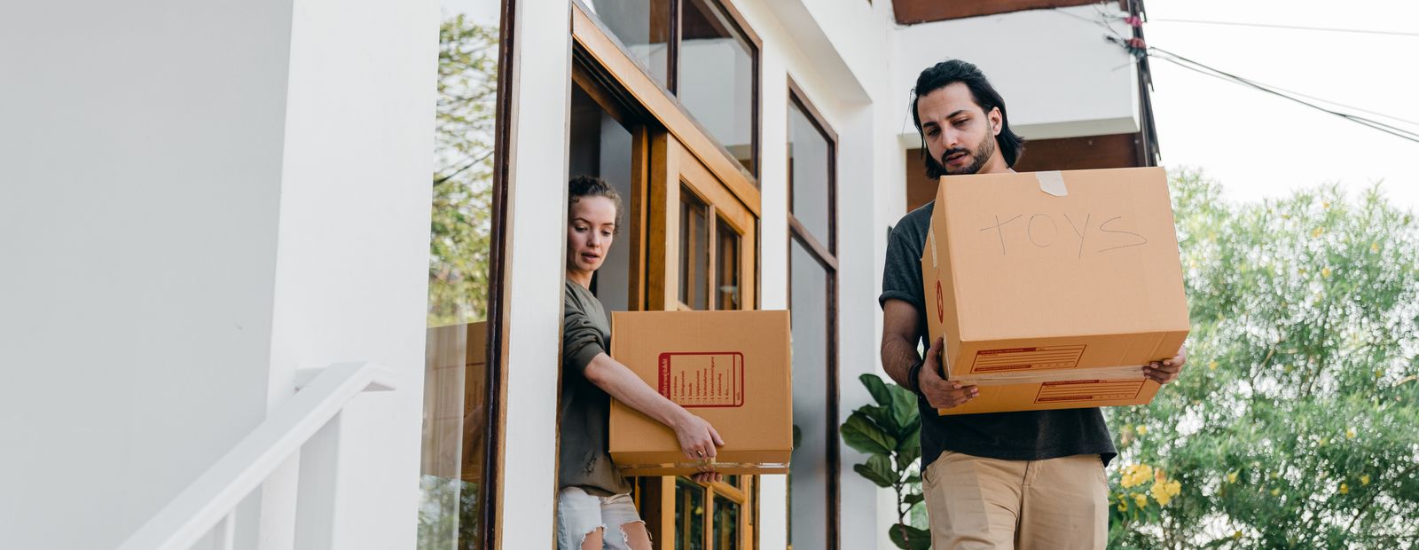 Couple carrying cardboard boxes while moving out of their home