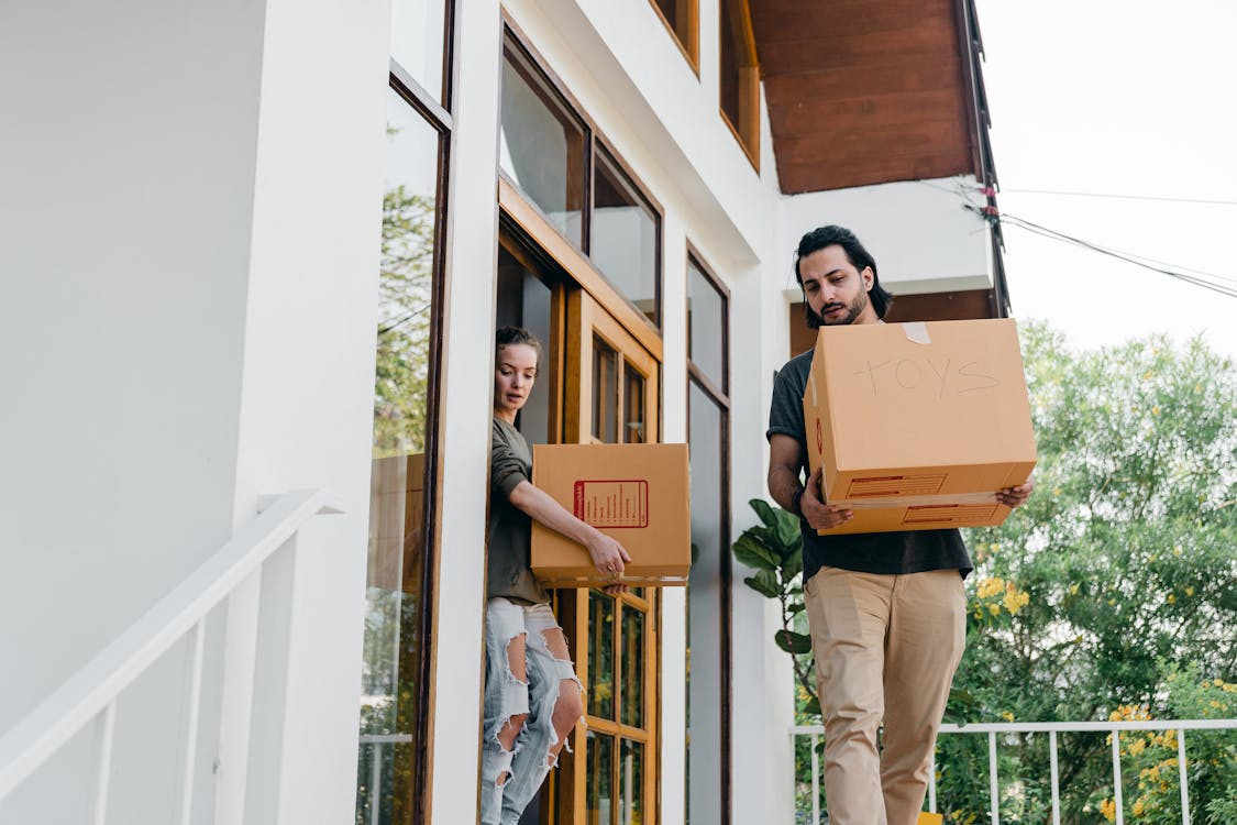 Free Couple carrying carton boxes while moving out of old home Stock Photo