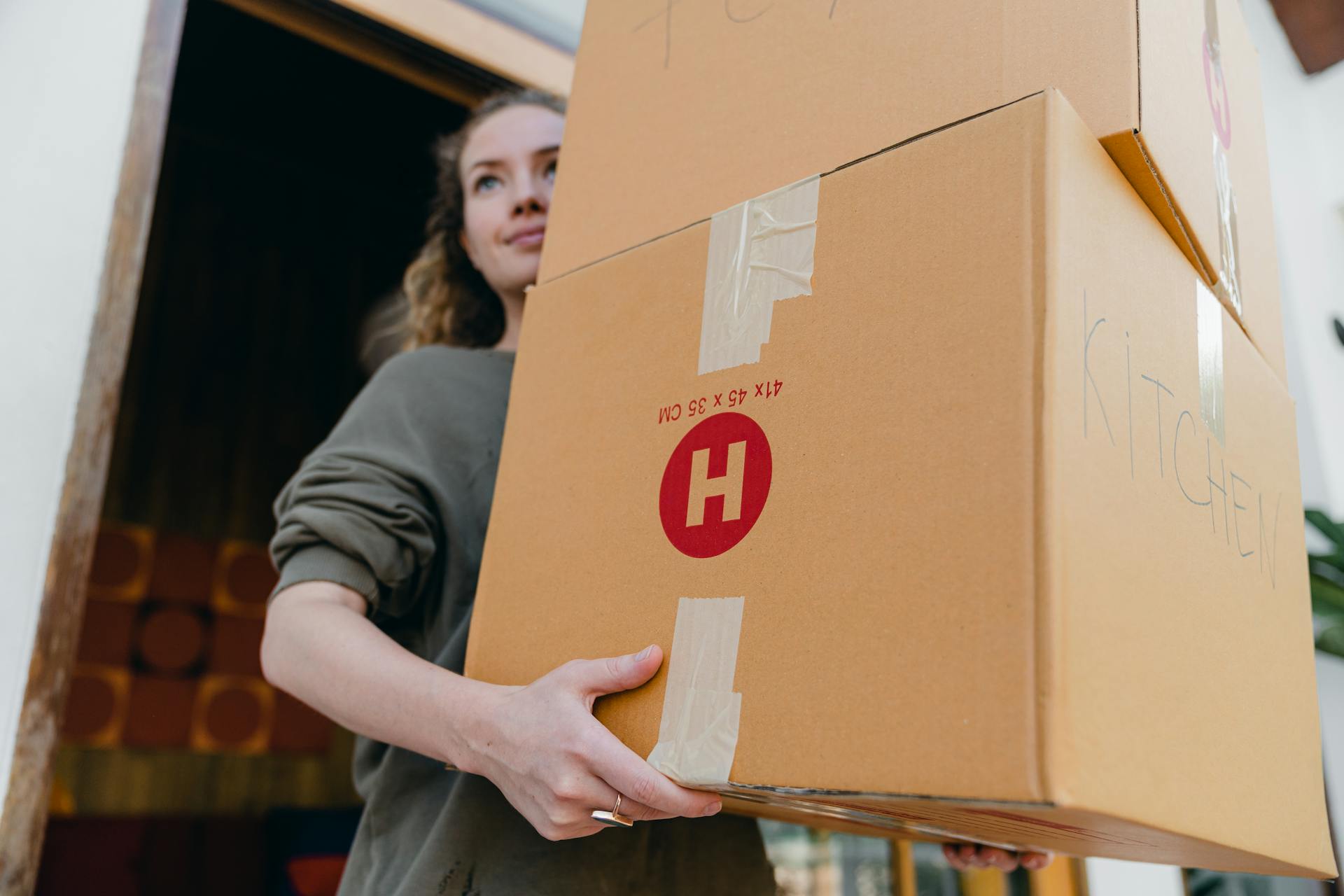 Confident young woman carrying cardboard boxes during a move out day.