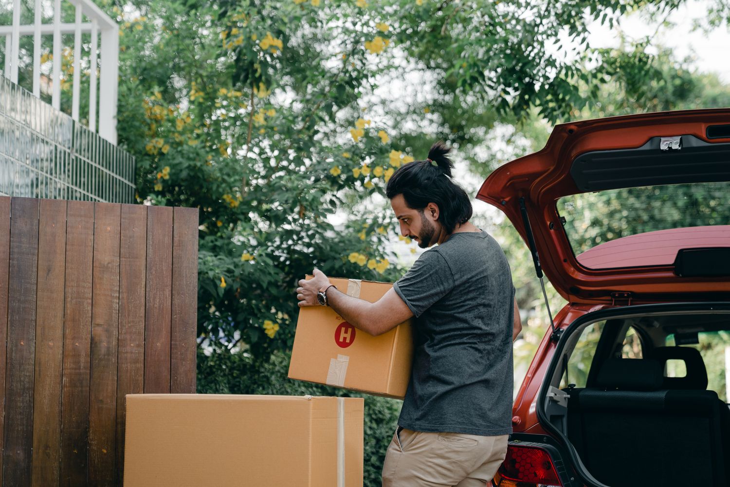 Man bending at the knees to lift a large box into a vehicle using proper lifting technique