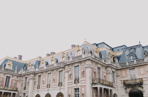 Free Exterior view of the Palace of Versailles showcasing classic French architecture with detailed sculptures. Stock Photo