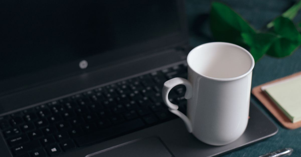 Espacio de trabajo limpio y moderno con un portátil y una taza blanca en el escritorio.