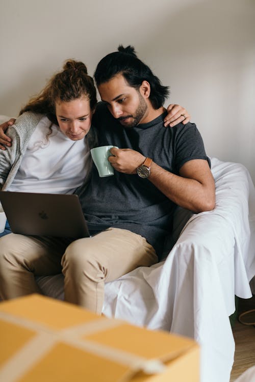 Free Multiethnic couple surfing net on laptop in new house Stock Photo