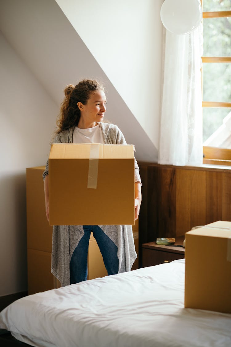 Happy Woman With Big Box In Bedroom Of New Home