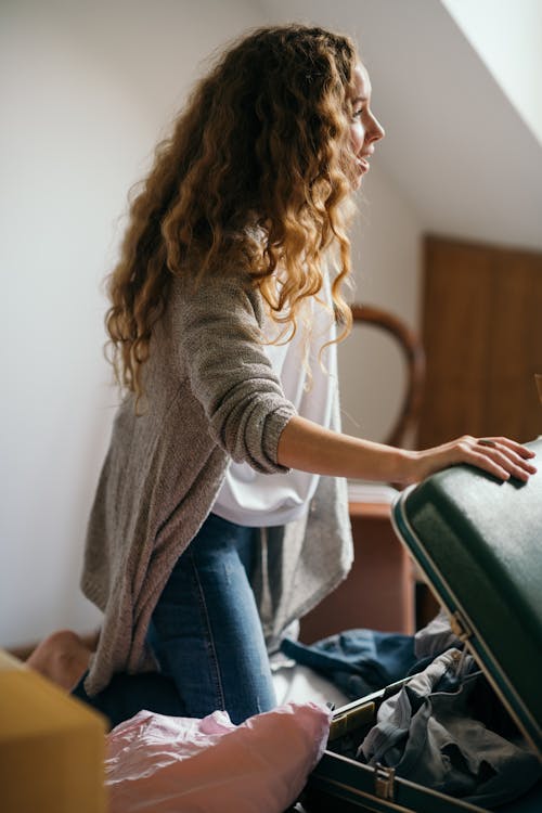 Focused woman packing suitcase in bedroom