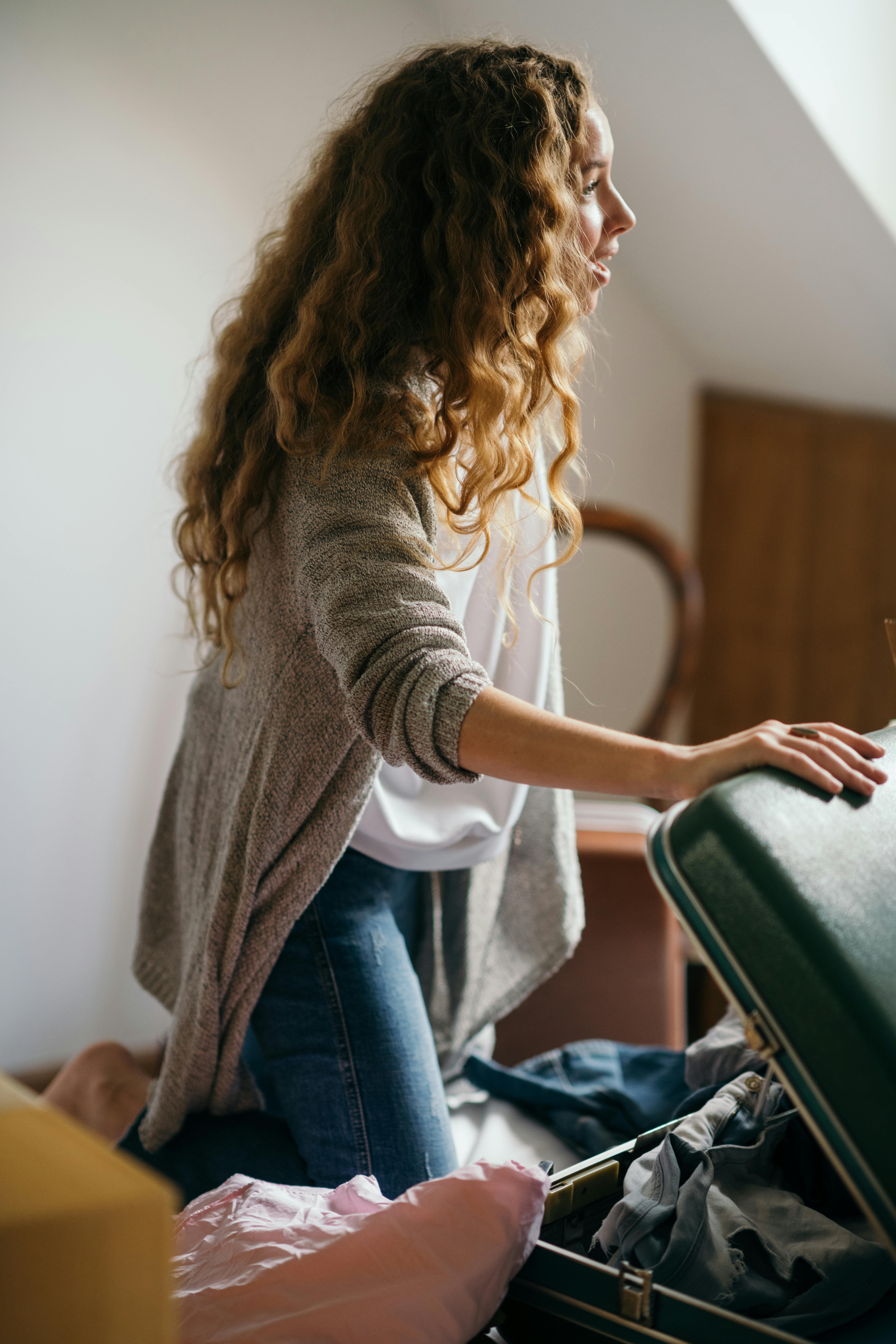 Crop woman packing suitcase on bed - a Royalty Free Stock Photo