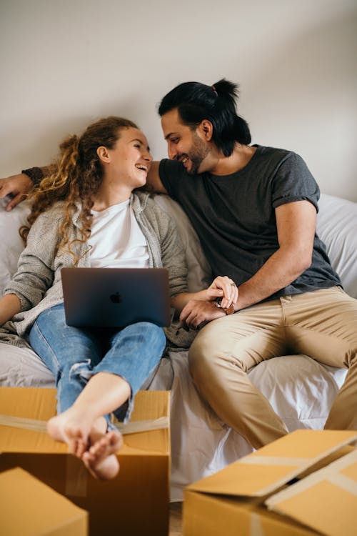 Laughing couple having break on sofa after relocating