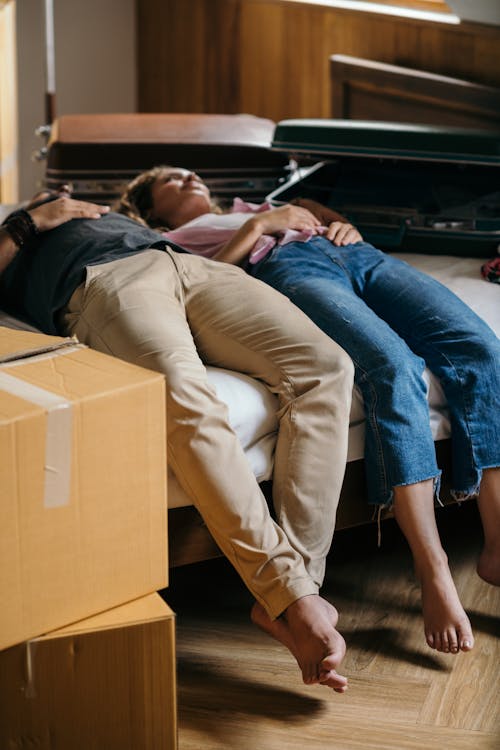 Free Tired couple lying on bed near boxes Stock Photo